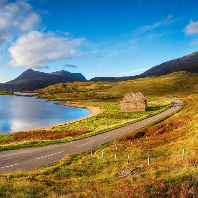 Autumn at Loch Assynt in Scotland with the ruins of Calda House and Ardvreck Castle in the far left, landmarks on the NC500 scenic driving route