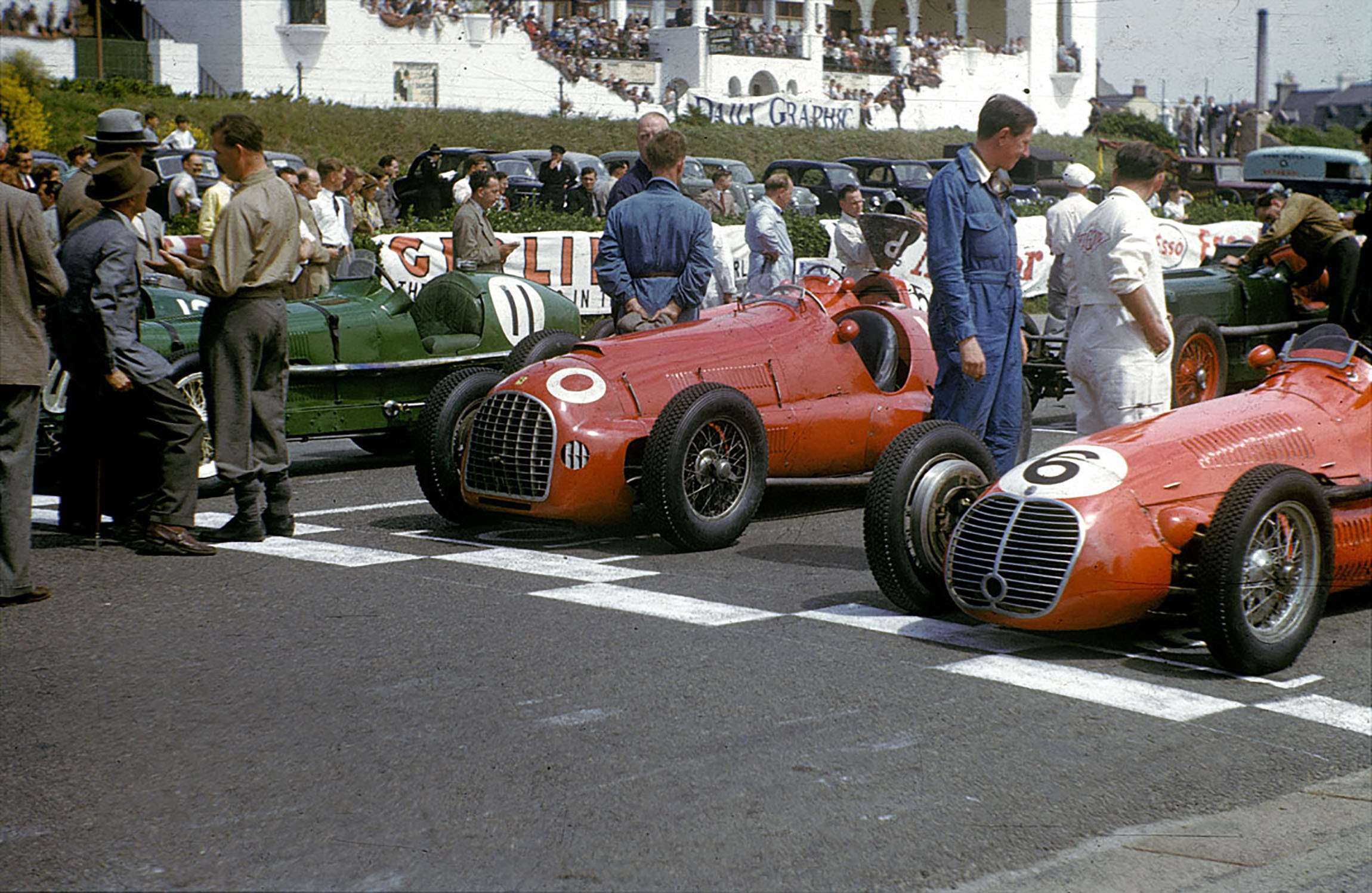 Freddie March (left on shooting stick) talking with Peter Whitehead - trousers tucked in socks - whose Ferrari 125 sits there on the 1950 Jersey Road Race front row.