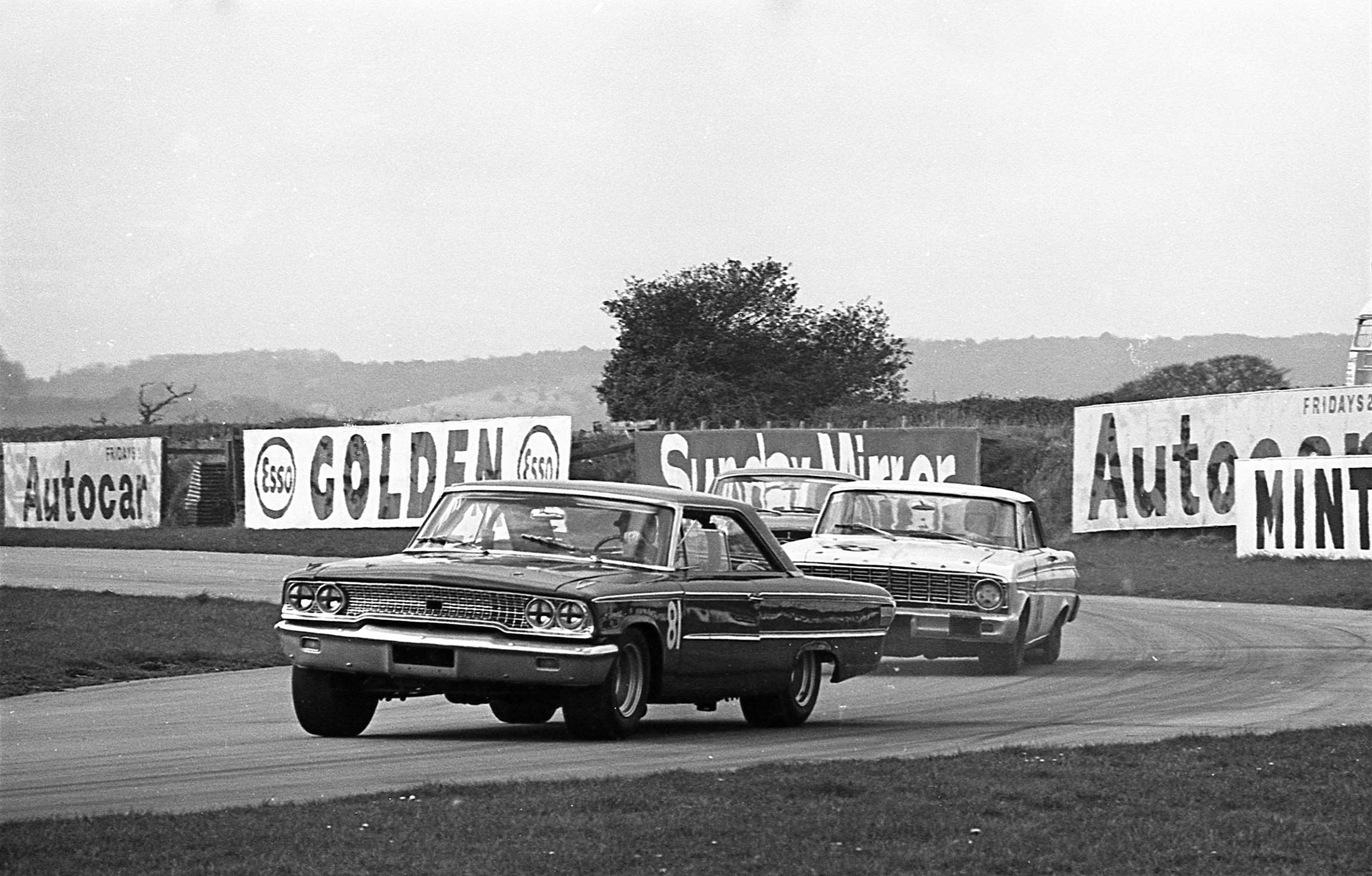 Brian Muir in the John Willment Ford Galaxe leads Sir Gawaine Baillie’s Ford Falcon at Woodcote Corner