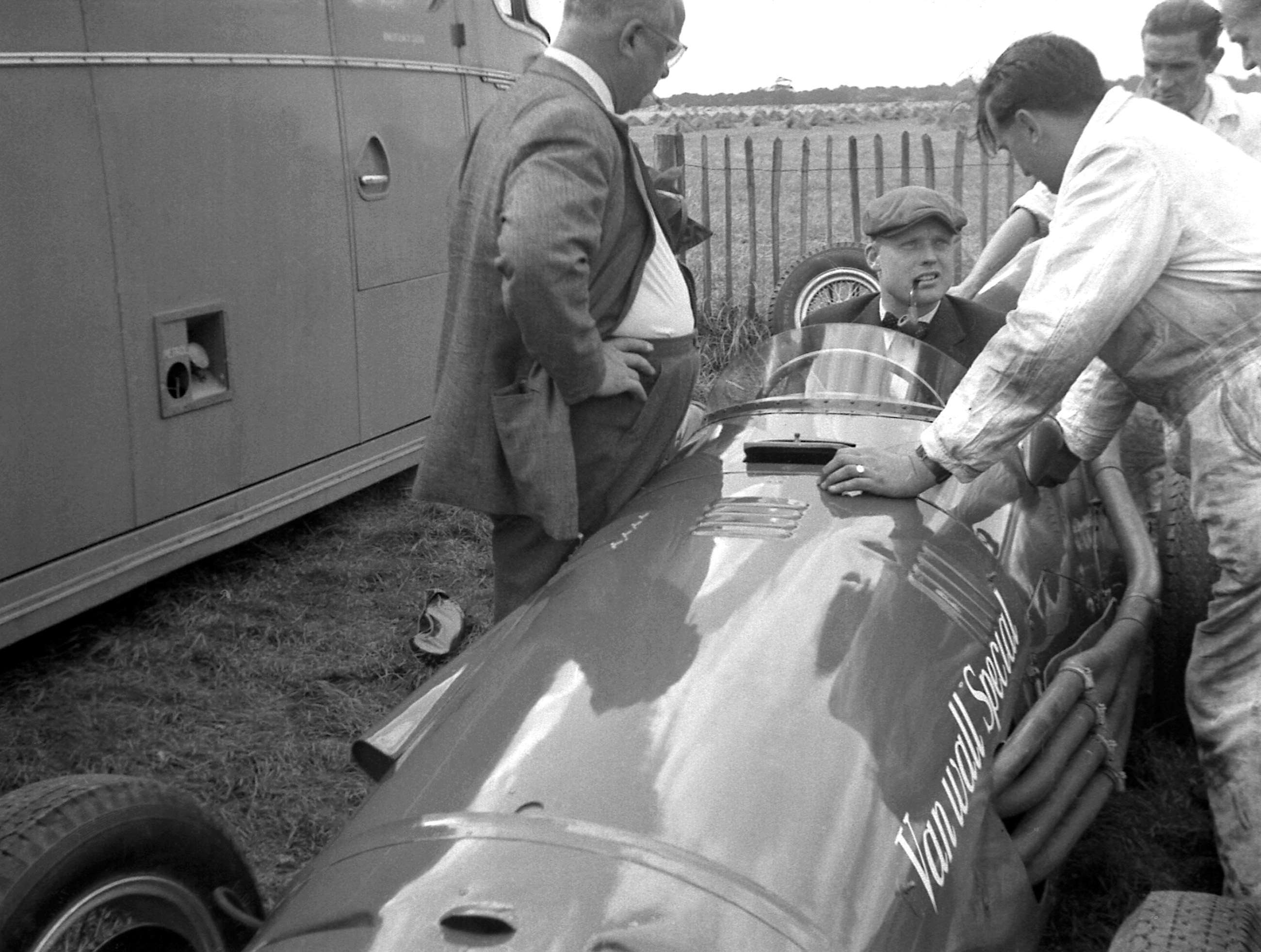 Mike Hawthorn seated in the 4.5-litre V12-engined Ferrari ‘ThinWall Special’ in the Goodwood paddock, owner Tony Vandervell standing left.