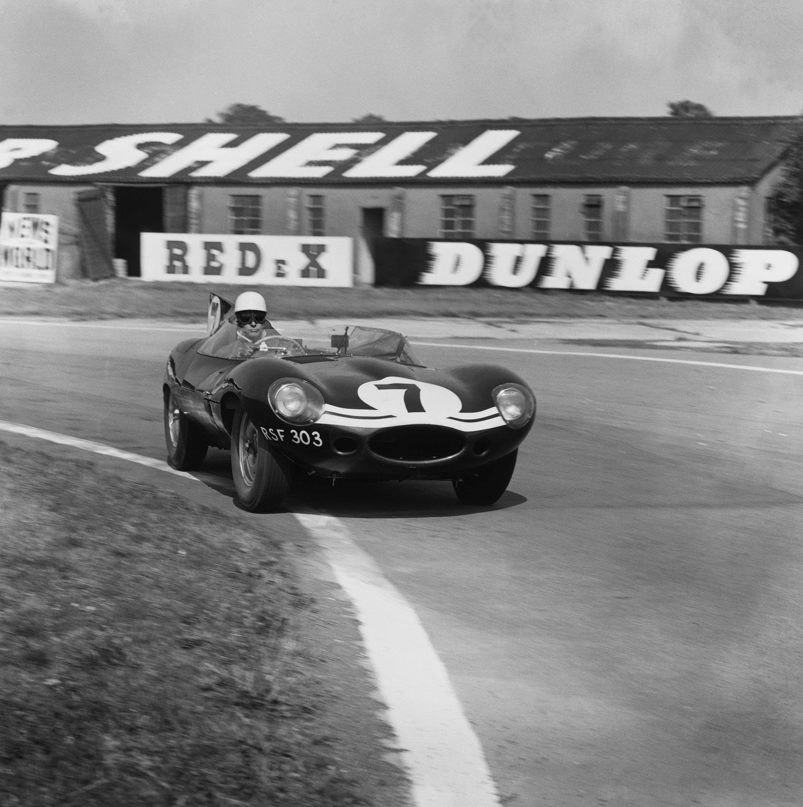 The Jaguar D-Type of Ron Flockhard and John Bekaert steaming past the Supershell building at Goodwood, 1959.