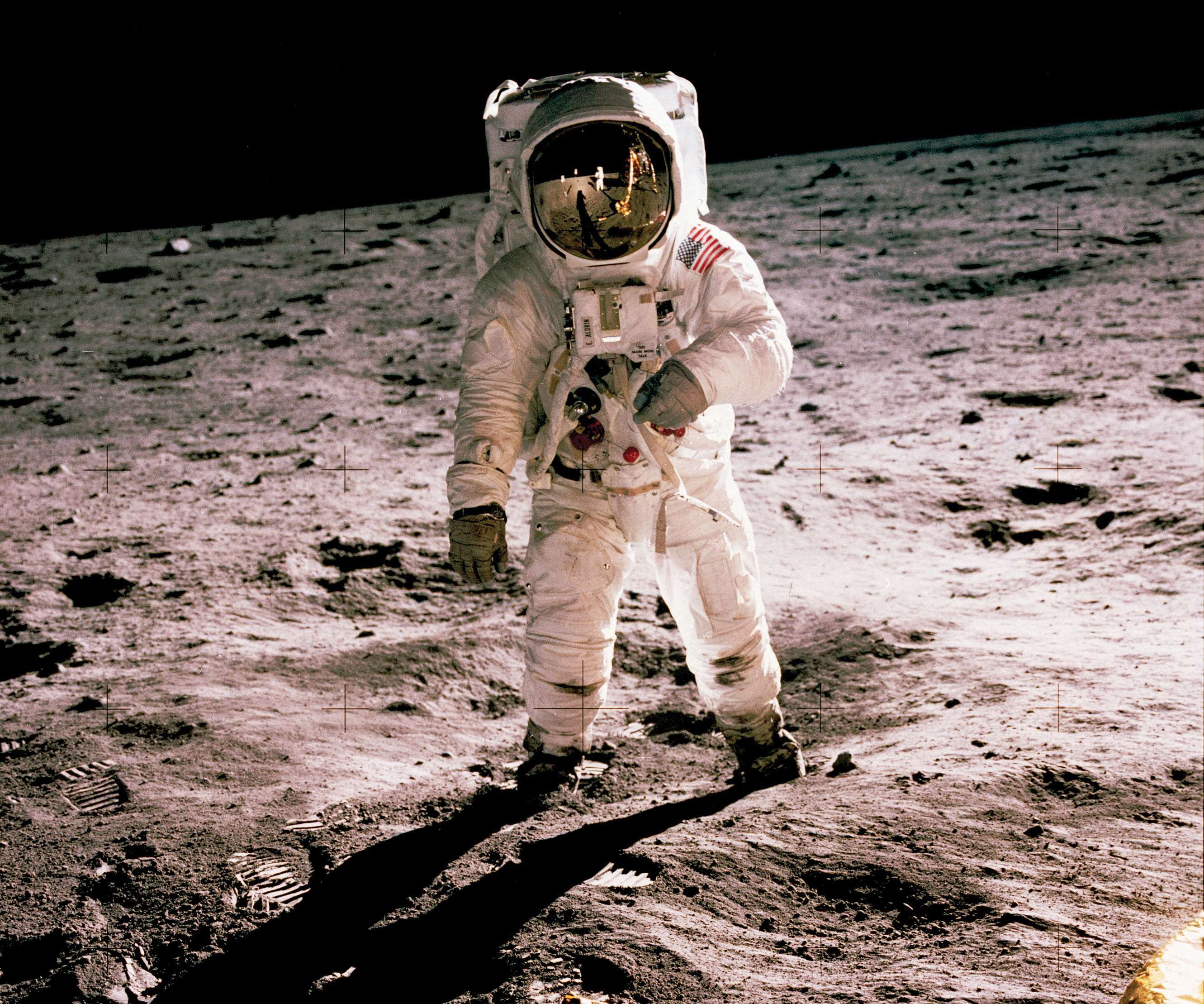 Buzz Aldrin walks on the Moon. Neil Armstrong, who took the photo, can be seen reflected in his helmet. 