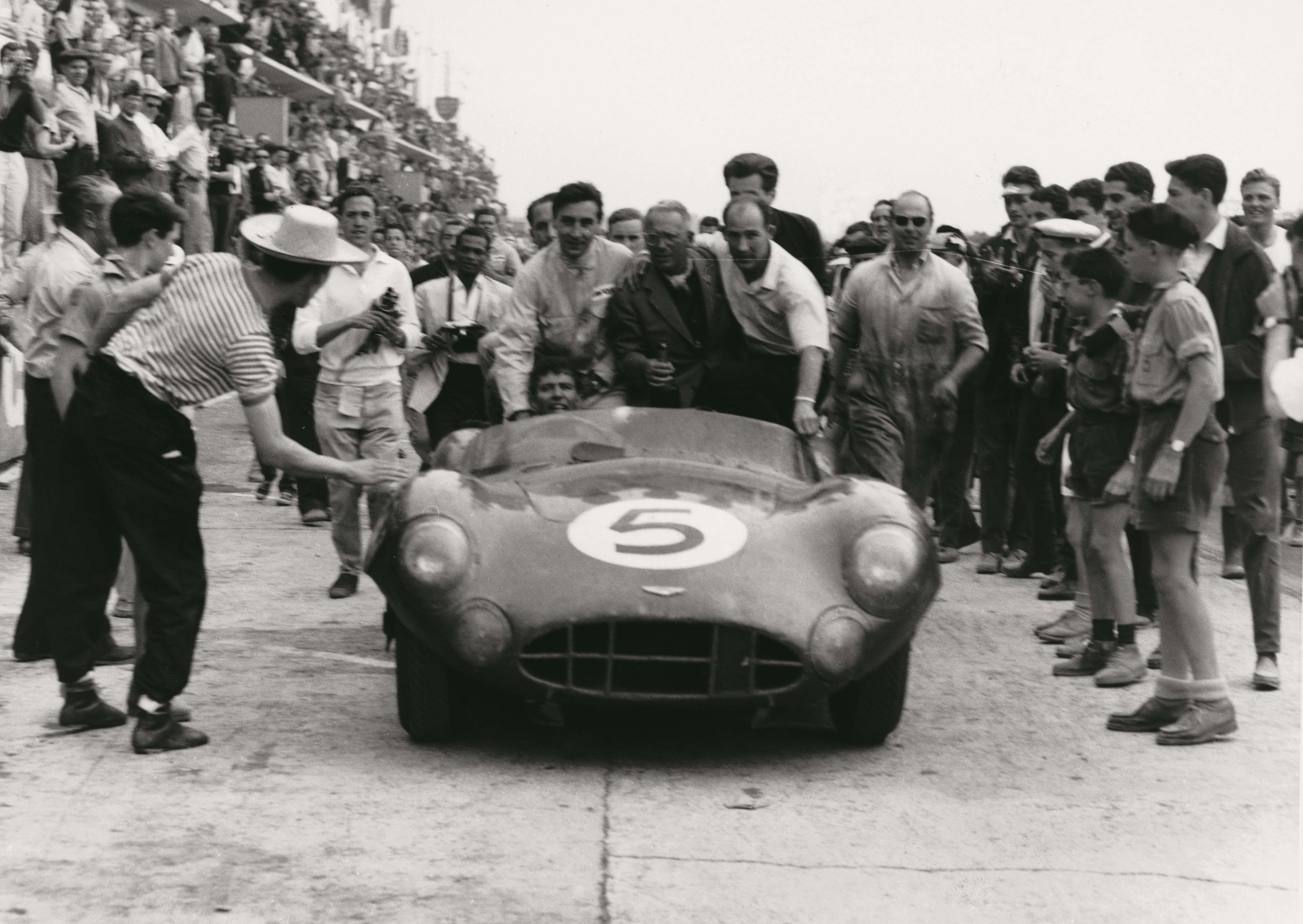  Carroll Shelby drives the victorious DBR1 into parc fermé at Le Mans in 1959, with (from left to right) Roy Savadori, David Brown and Stirling Moss hitching a ride